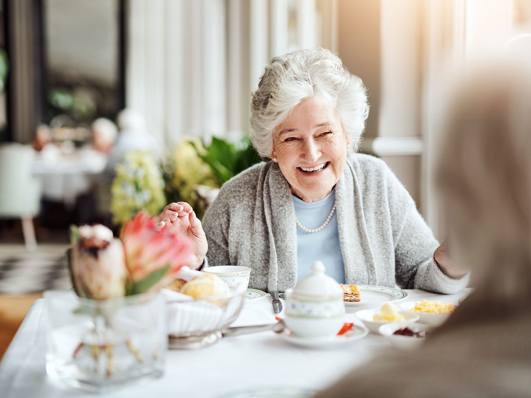 Kaffe und Kuchen: zwei ältere Damen unterhalten sich - lächelnd